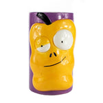 The Ceramic Monster Face Candle – Yellow resembles a cartoonish yellow apple with big eyes and a crooked mouth, similar to a whimsical ceramic mug, shown against a purple background.
