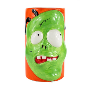 The Ceramic Monster Face Candle – Green is a ceramic mug with an orange background, featuring a raised cartoon green zombie face—bulging eyes and crooked teeth—perfect for a spooky Halloween candle display.