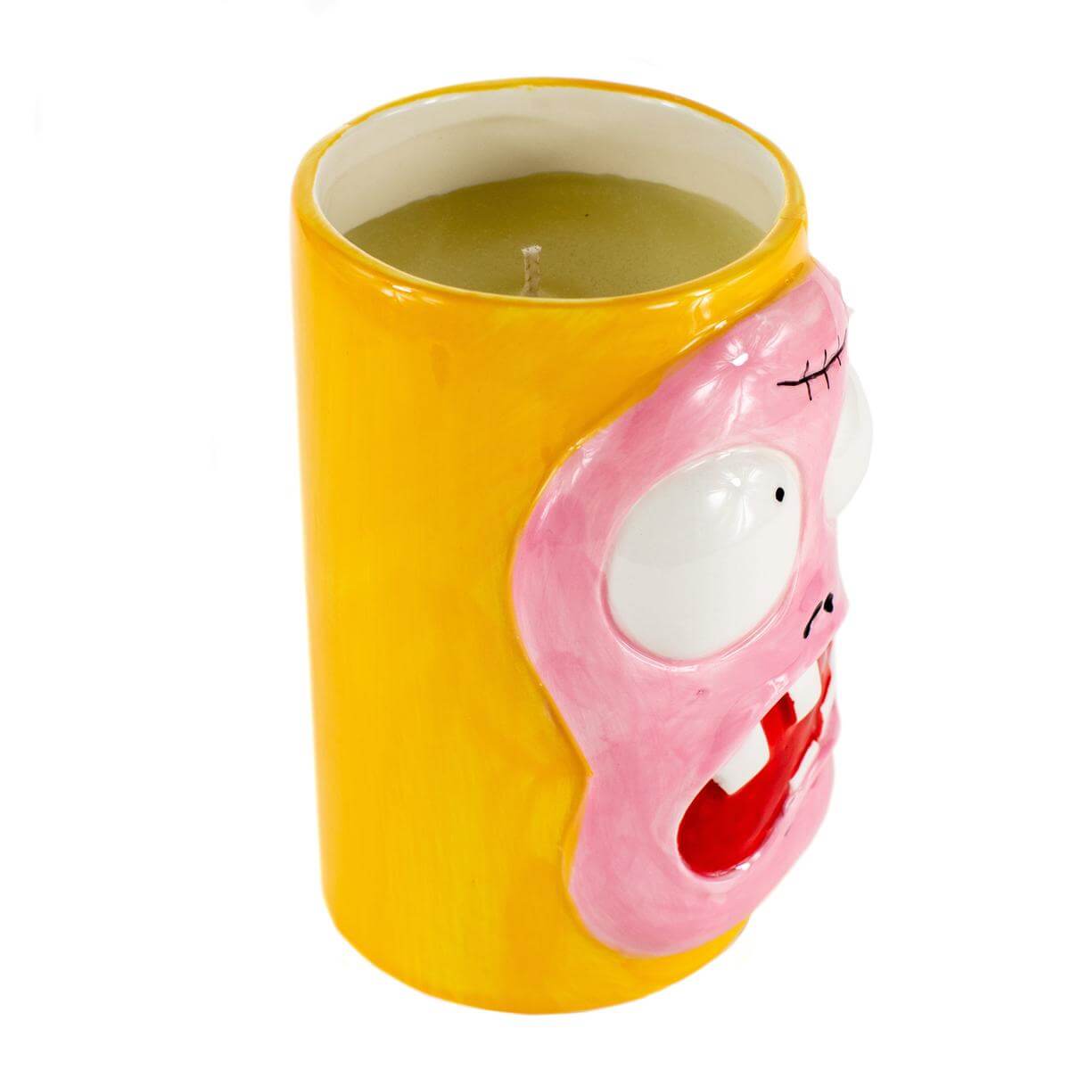 The Ceramic Monster Face Candle – Pink is a yellow cylindrical candle holder with a cartoonish pink face, large eyes, and an open mouth, containing a greenish soy wax candle inside.