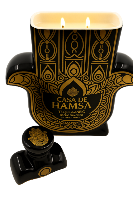 The Recycled Black and Gold Tequila Candle is crafted in the shape of a Hamsa hand, featuring intricate patterns, two candle-like flames, and Coconut Apricot wax, with the label "Casa de Hamsa Tequilanejo Hecho en México.