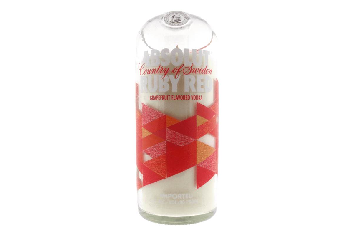 The Recycled Ruby Vodka Candle is hand-poured into an Absolut Ruby Red bottle and features a red and orange geometric label on a white background.