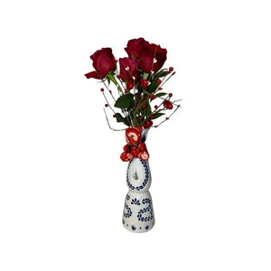 The Valentine Bouquets feature red roses and small red berries arranged in a white repurposed bottle vase with blue patterns—an eco-friendly, sustainable Valentine’s Day gift.