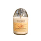 The Recycled Cognac Candle is a white candle in a glass container made from recycled cognac bottles, featuring a Rémy Martin 1738 label and topped with a metal medallion.