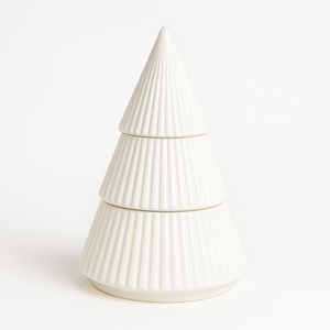 The White Ceramic Christmas Tree Candle is a ribbed, tiered ceramic candle shaped like a festive tree, crafted with all-natural wax and displayed against a plain white background.