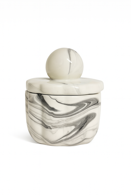 The Marble Luxe Candle is a small, round ceramic container with a marbled black and white design, featuring a matching lid topped with a spherical handle for added elegance.