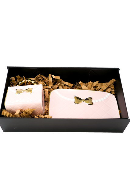 A black gift box holds two pink, bow-adorned packages with gold accents—each containing a 3D Design Handbag Shaped Ceramic Coffee Cups Set—nestled in brown crinkle paper.