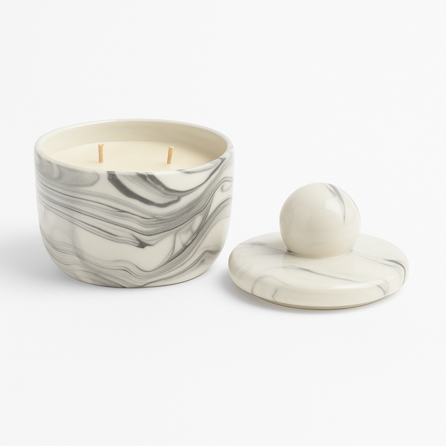 The Marble Luxe Candle, featuring two wicks and a marble-patterned round design in elegant white and grey, sits beside its matching lid.