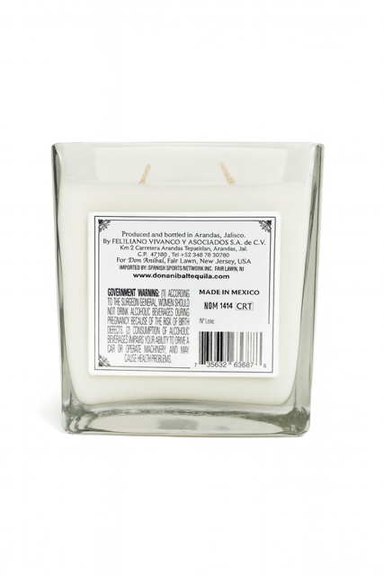 The Recycled Silver Tequila Candle features a square glass design, white soy wax with two wicks, and a side label with manufacturer info, website, barcode, and government warning. This candle adds a unique touch to any setting.
