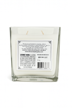 The Recycled Silver Tequila Candle features a square glass design, white soy wax with two wicks, and a side label with manufacturer info, website, barcode, and government warning. This candle adds a unique touch to any setting.
