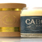 The Recycled Azul Agave Reposado Tequila Candle, in a glass labeled "Cabo Wabo Tequila Reposado," sits beside a gold-accented cylindrical box, making it the perfect eco-friendly decor accent.