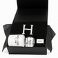 The Paris Designer Gift Set includes a black gift box with a black item featuring a white "H," a white Hermès candle, a silver Hermès cup, and a cotton throw—an elegant choice for those who value custom-designed gift baskets.