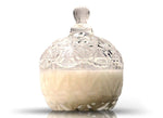 The Sugar Dish Motif Candle is a clear, ornate glass jar with a lid, half-filled with white soy wax, displayed against a white background.