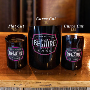 Three black Luc Belaire Rare Rosé bottles—a 750mL flat cut, a 3L curve cut, and a 1.5L curve cut—are upcycled as containers, including a Recycled Rare Rosé Champagne Candle, all displayed on wood.