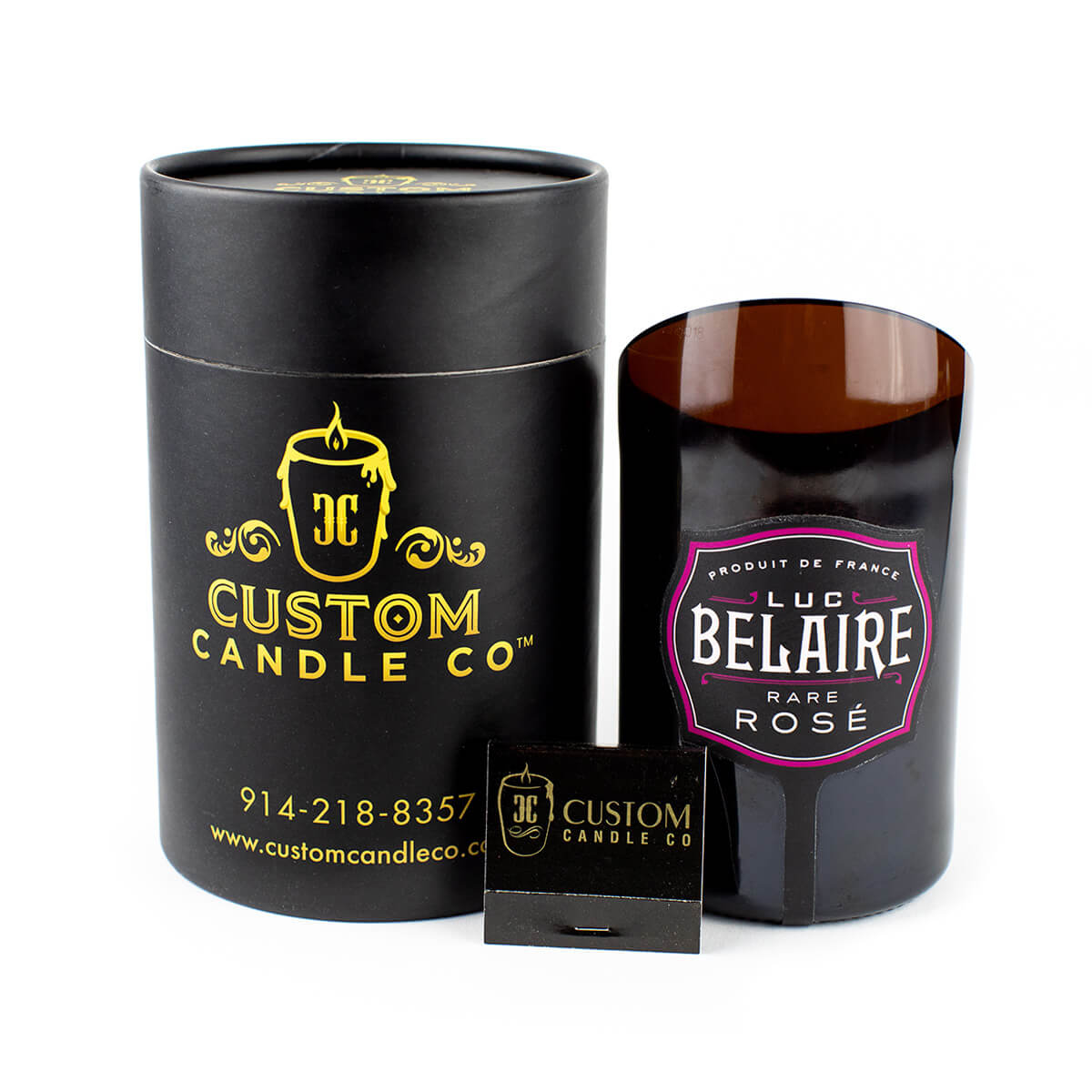 The Recycled Rare Rosé Champagne Candle, labeled "Luc Belaire Rare Rosé," sits beside a black Custom Candle Co. box and a small black matchbox, showcasing this unique upcycled candle.