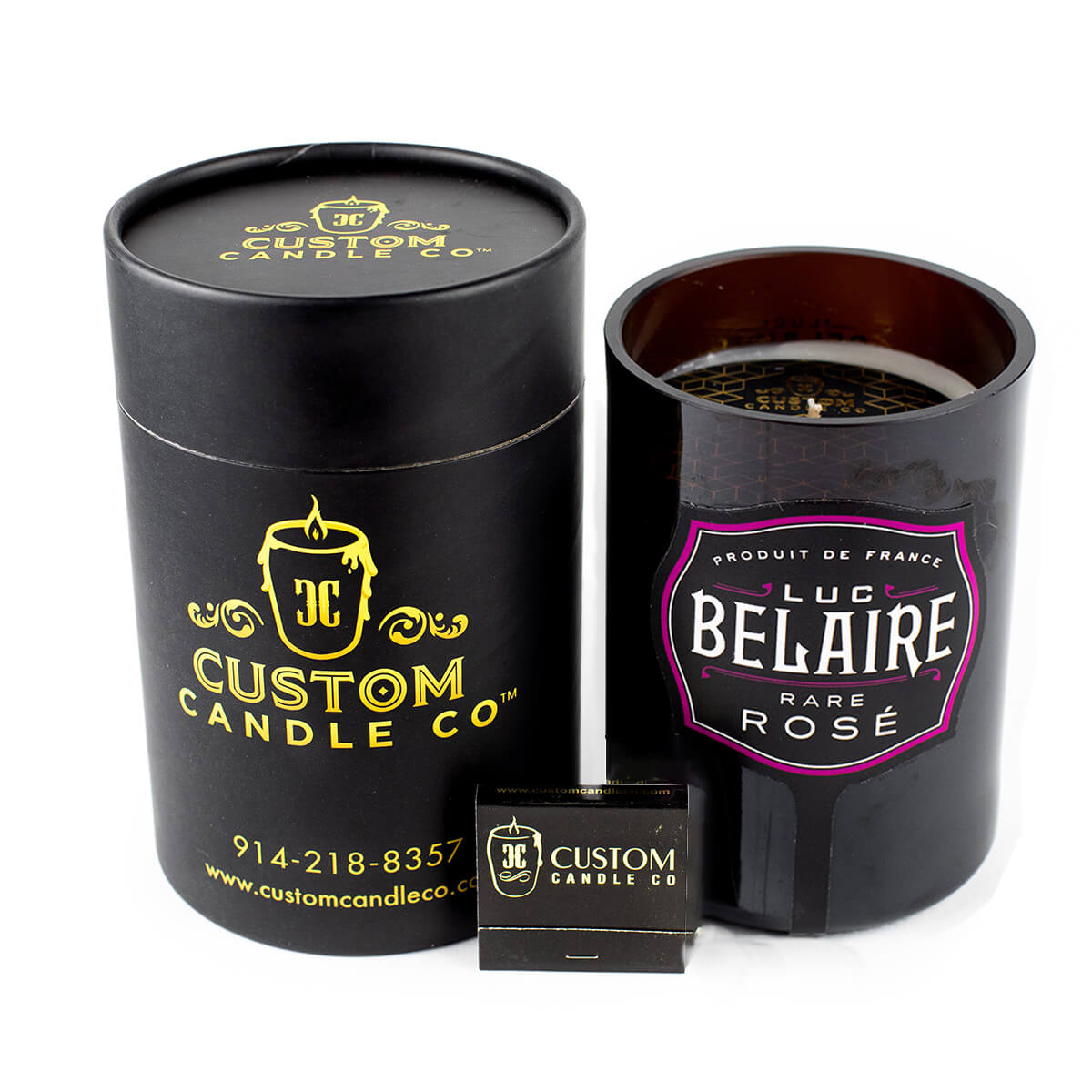 A Recycled Rare Rosé Champagne Candle by Custom Candle Co. is shown in black with its cylindrical packaging and a matchbox beside it.