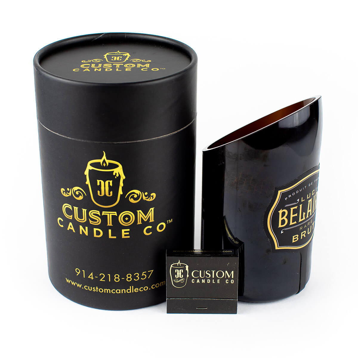 The Recycled Black Champagne Candle features black cylindrical packaging with "Custom Candle Co." branding, an open all-natural soy candle in a recycled black champagne glass, and a small branded matchbox displayed in front.
