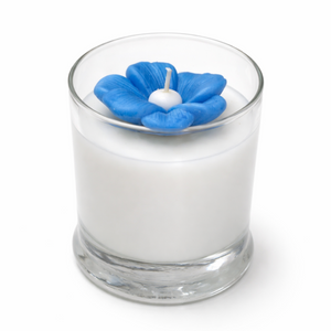 The Blue Blossom Candle is a handcrafted white soy candle in a clear glass holder, topped with a blue flower-shaped decoration and wick.