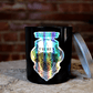 The Zodiac: Taurus Candle, featuring a holographic bull design and black jar, sits on a wooden surface with its silver lid beside it. A brick wall is visible in the background.