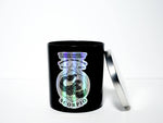 The Zodiac: Scorpio Candle features a black jar with astrological dates, a holographic design, and a silver lid, shown resting beside it on a white background.