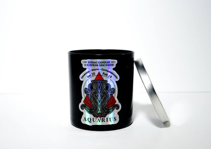 The Zodiac: Aquarius Candle features a black jar with a decorative zodiac design and silver lid, made from natural soy wax, and includes a surprise gem hidden inside.