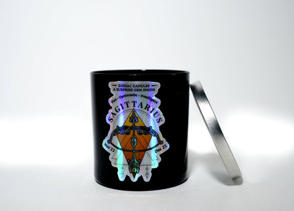 The Zodiac: Sagittarius Candle is a black soy jar with a metallic lid, labeled "Sagittarius" and decorated with zodiac graphics; it also includes a hidden surprise gem inside.