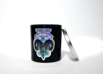 The Zodiac: Aries Candle features a black jar with a ram graphic and zodiac dates beside a silver lid on a white background—a chic soy candle ideal for astrology lovers.