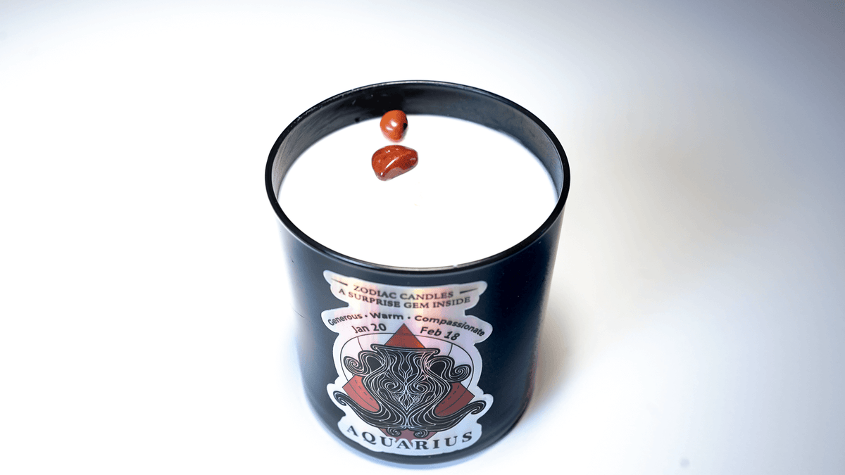 The Zodiac: Aquarius Candle is a black candle with white soy wax and two small brown stones on top—perfect for celebrating your star sign.
