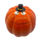 The Ceramic Orange Halloween Pumpkin Candle w/ Hat Lid features a pumpkin face and a small black top hat, ideal for displaying your favorite fall candle. Shown on a white background.
