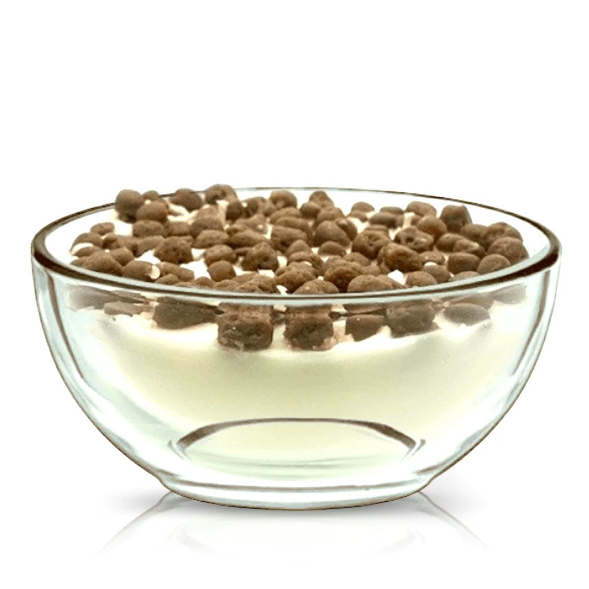A clear reusable cereal bowl holds a Cereal Puffy Coco Candle, designed to look like white yogurt topped with small round chocolate cereal pieces, set against a white background.