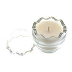 The Clear Glass Easter Egg is a white natural wax candle in a round, clear glass container with a wavy edge and matching lid, featuring a subtle peeps fragrance.