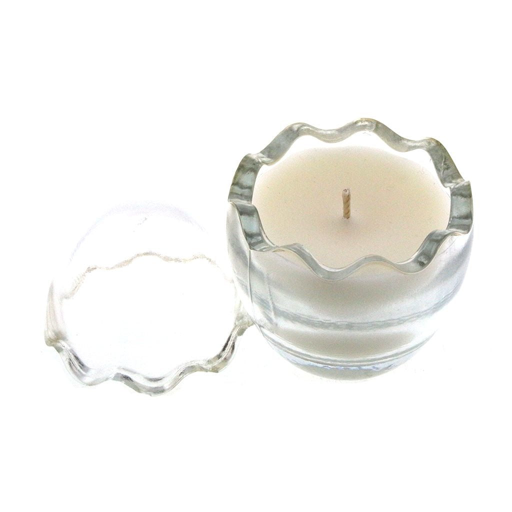 The Clear Glass Easter Egg is a white natural wax candle in a round, clear glass container with a wavy edge and matching lid, featuring a subtle peeps fragrance.