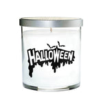 The Clear Tumbler Halloween Candle features white soy wax in a clear glass jar with a silver lid, labeled "HALLOWEEN" in bold black letters and bat graphics—perfect for adding spooky scent to your nights.