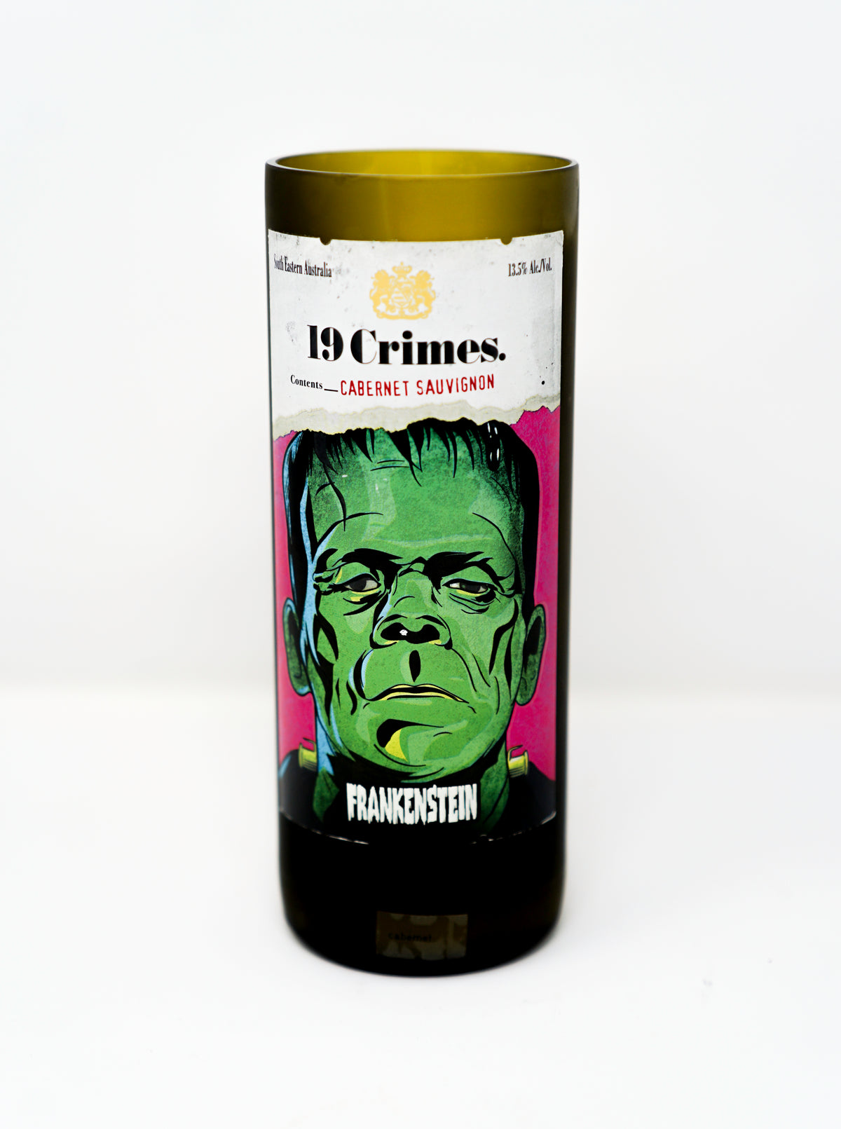 The Recycled Frankenstein Candle is made from a green glass 19 Crimes Cabernet Sauvignon wine bottle with a Frankenstein illustration label, upcycled into a unique recycled bottle candle.