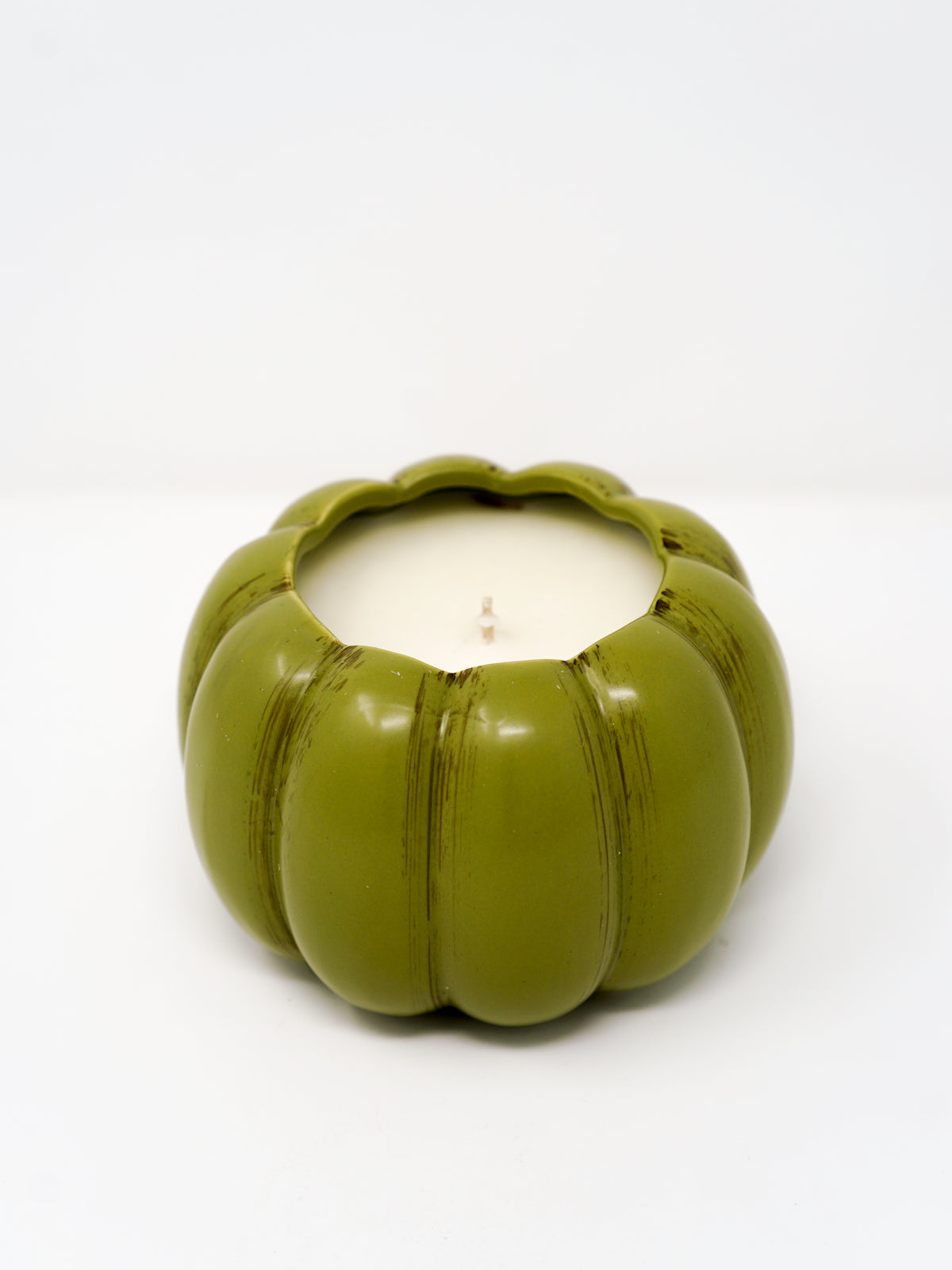 The Ceramic Pumpkin Vessel Candle, featuring natural soy wax in a white ceramic pumpkin, sits on a white surface and evokes autumn’s charm with its seasonal scent against a simple backdrop.