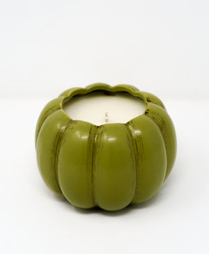 The Ceramic Pumpkin Vessel Candle features a green, pumpkin-shaped ceramic container with a white candle inside, ideal for autumn scents. Shown here against a plain white background.