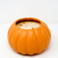A partially used white soy wax candle is housed in a pumpkin-shaped orange ceramic Pumpkin Vessel Candle, shown against a plain white background.
