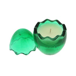 The Green Glass Easter Egg features a round, green glass holder with a wavy-edged lid beside it, revealing an egg-shaped candle made from all-natural wax inside.