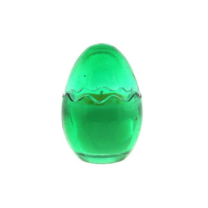 The Green Glass Easter Egg w/ Yoke is an egg-shaped candle crafted from natural wax with a wavy seam around the middle, shown on a white background.
