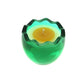 The Green Glass Easter Egg w/ Yoke is a green glass candle holder with a scalloped edge, containing an egg-shaped natural wax candle with a yellow center and white outer ring, shown on a white background.
