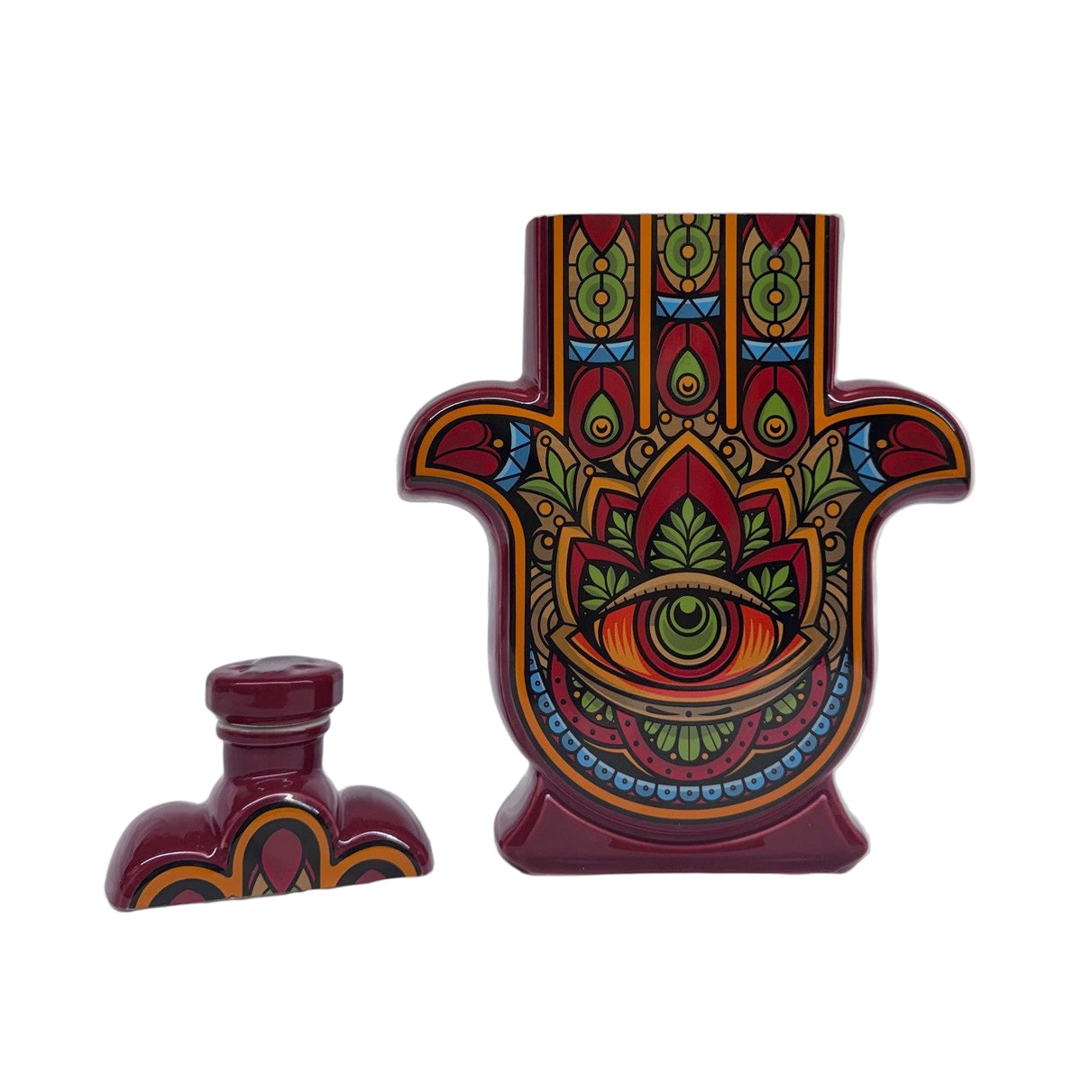 A recycled Reposado Tequila Candle in a ceramic Hamsa hand bottle features colorful patterns and an eye motif, with its matching cap beside it. Perfect for displaying as art or enjoying as a natural soy candle.