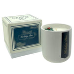 The Holiday Scented Boxed Candle – Holiday Pine Scent is shown in a white ceramic holder labeled "Holiday Pine" beside its matching navy and white box, featuring a fresh pine fragrance made from natural soy wax.