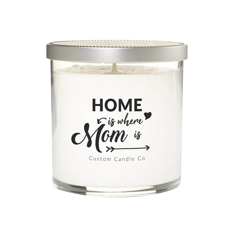A hand-poured soy candle in a white glass jar with a silver lid. The label says: "Home is where mom is" Custom Candle Co in black decorative text.