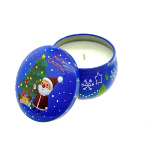 The Dark Blue Santa Holiday Tin Candle features a "Merry Christmas" message and Santa by a tree on a round soy wax candle, shown with the lid off. Enjoy the festive Christmas Garland scent.