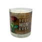 The Best Mom Ever quoted candle with box features a label with a red rose and "BEST MOM EVER" text on a brown background. Crafted from soy wax, it offers a soothing amber scent to fill any space with comfort.