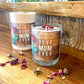 The Best Mom Ever quoted candle with box – Amber Scent, made from soy wax, sits on a wooden surface surrounded by scattered dried flower petals.