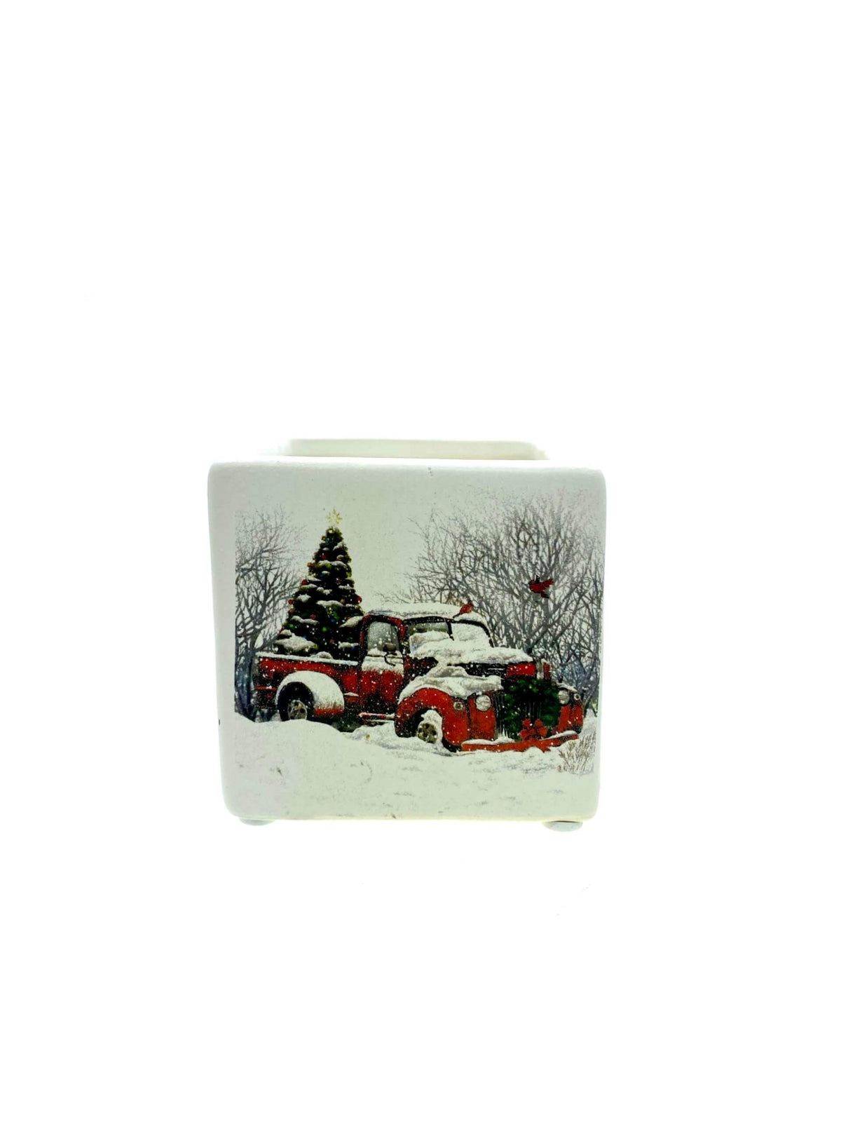 The Mini Square Christmas Candle (Snow Design) features a white ceramic holder with festive red trucks, a Christmas tree, and snowy trees—perfect for filling your home with holiday sparkle scent this season.