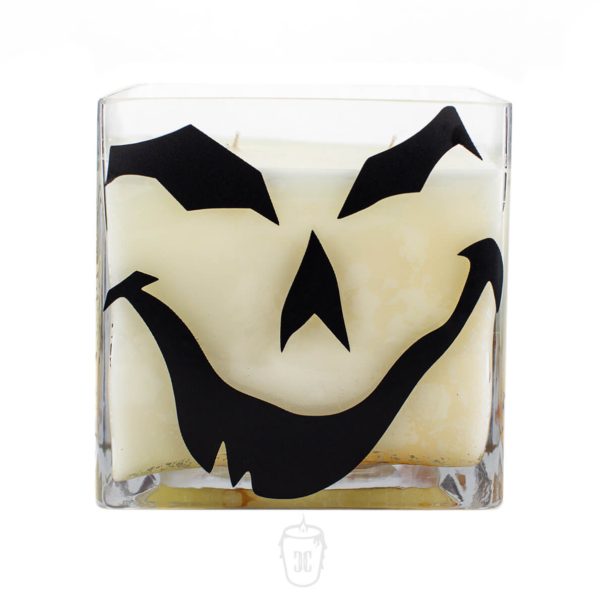 The Jack O’lantern Cube Candle is a white soy, 4-wick candle in a glass container with a black jack-o'-lantern face on the front.