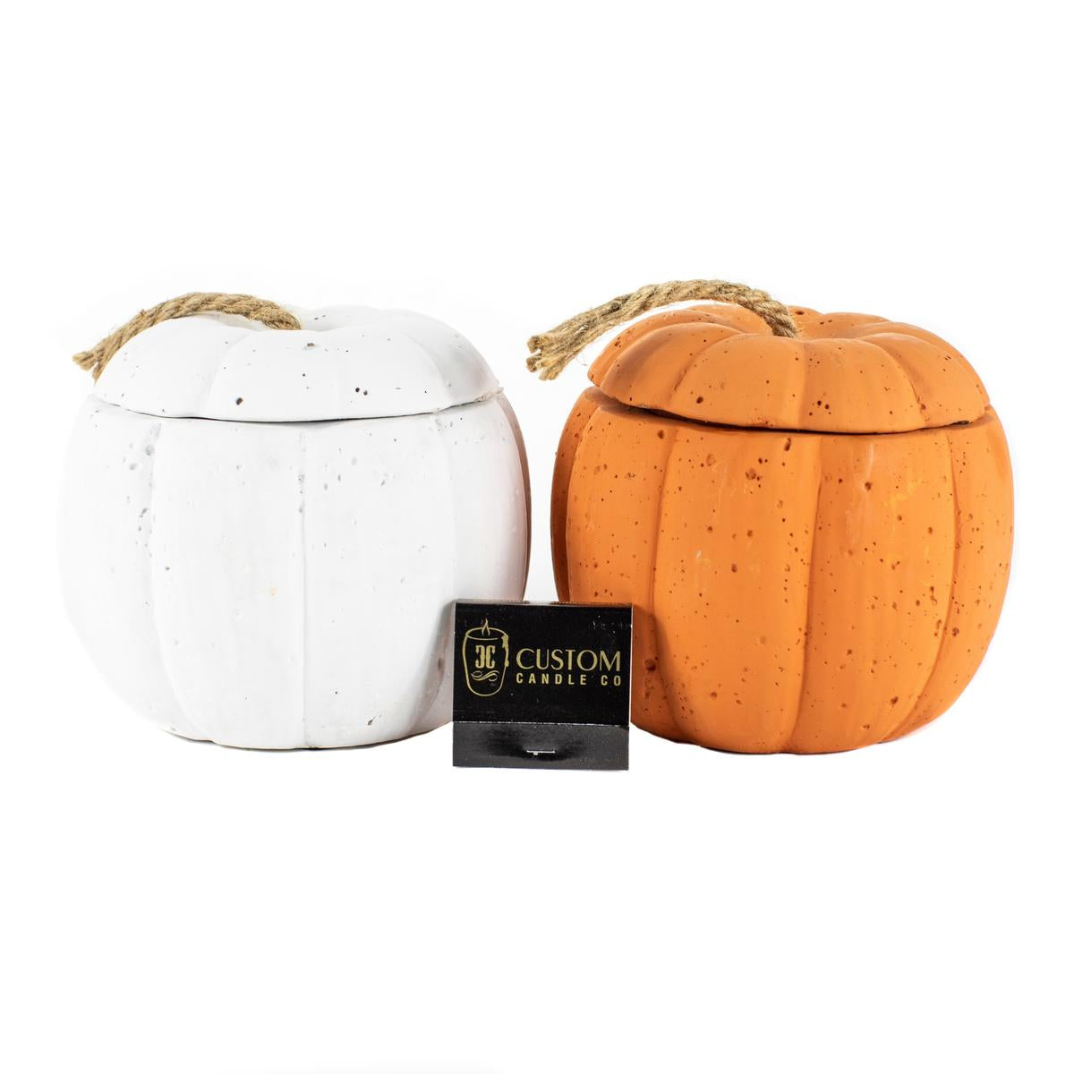 Displayed beside a black "JC Custom Candle Co." box, two pumpkin-shaped containers—one white, one orange—feature rope handles and are ideal for showcasing the Orange Cement Pumpkin Candle or your favorite custom candle.