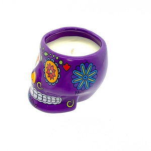 The Large Purple Ceramic Skull Candle – Nutmeg Scented, inspired by Día de los Muertos and adorned with colorful floral designs, is displayed on a white background.