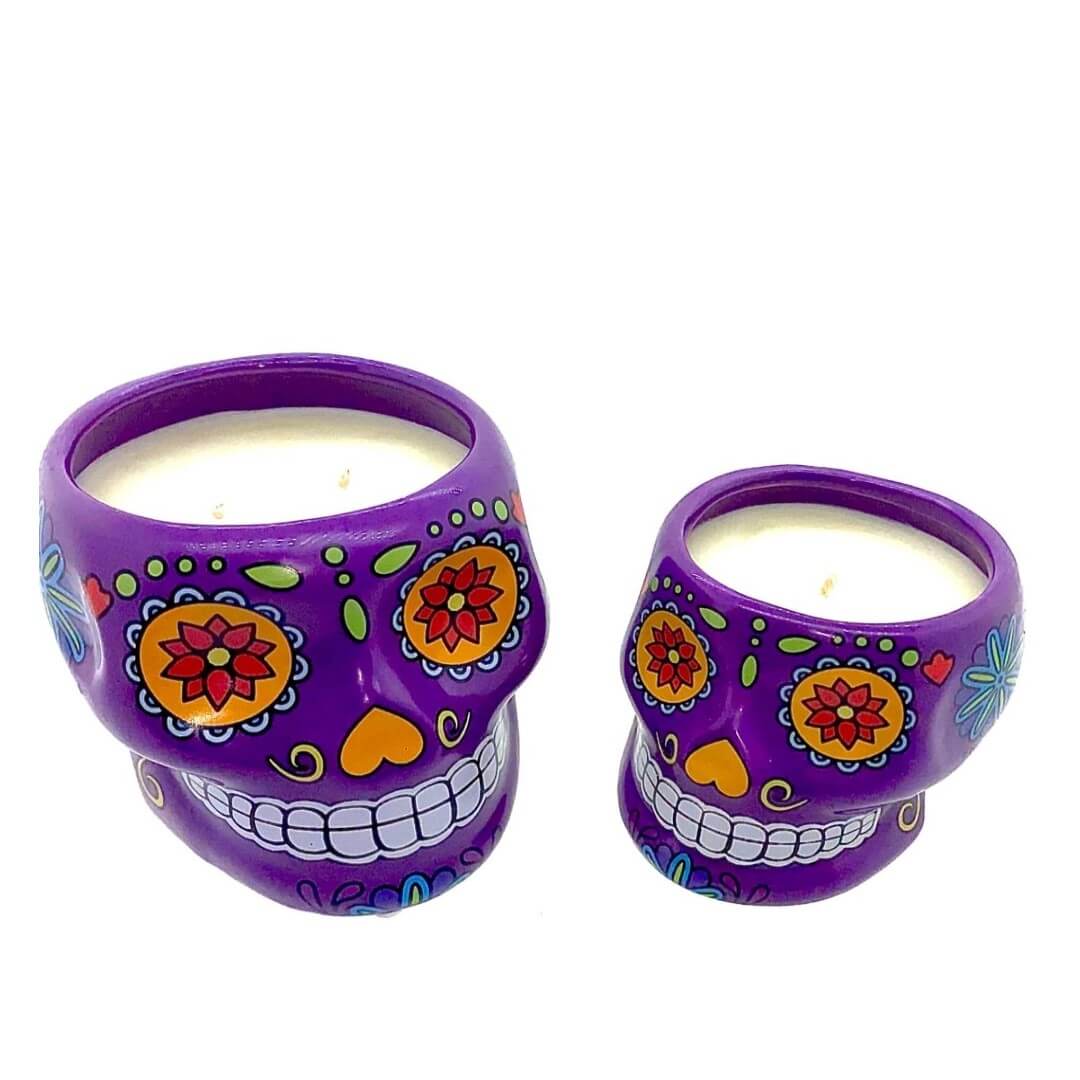 The Large Purple Ceramic Skull Candle – Nutmeg Scented features a vibrant sugar skull design and bright patterns, displayed against a white background. This candle adds a festive, aromatic touch to any room.
